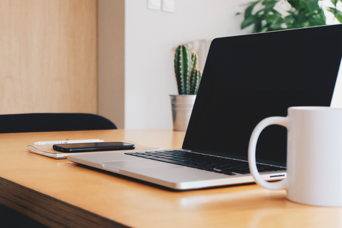 Zero waste tips - Canva stock image of a laptop on a desk with a ceramic mug and potted plants in the background