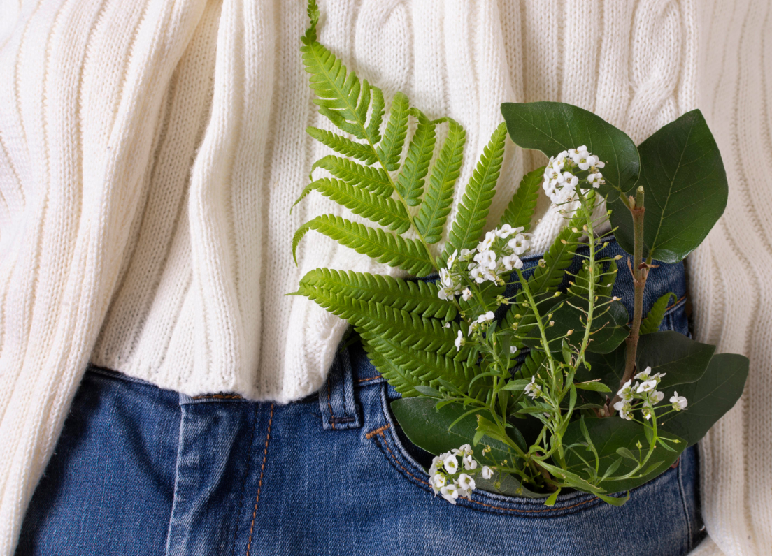 Sustainable fashion - concept image of blue jeans with flowers and ferns coming out of the pocket