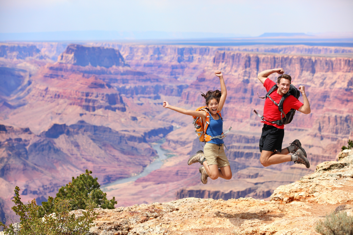 eco-friendly vacation - stock image from, canva of a couple jumping in the air with the grand canyon in the background