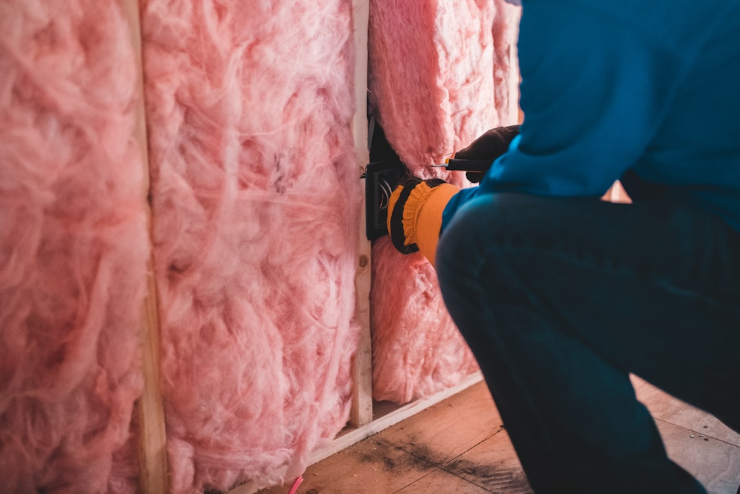 person in blue pants installing insulation